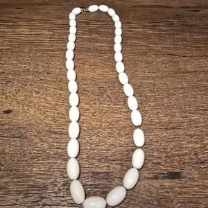 white beaded necklace on a gold tone chain